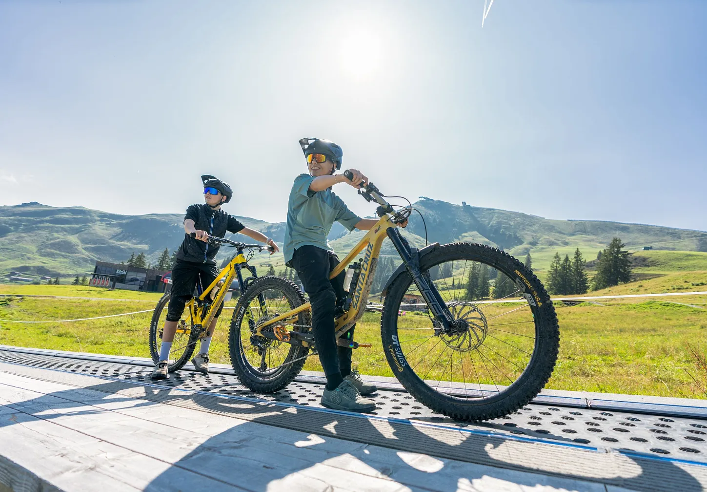 Zwei Personen stehen mit E-Mountainbikes auf einer Aussichtsplattform in den Bergen.