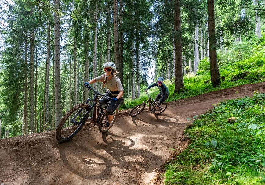 Zwei Mountainbiker fahren auf dem Hahnenkamm Trail im Wald nach Kitzbühel.